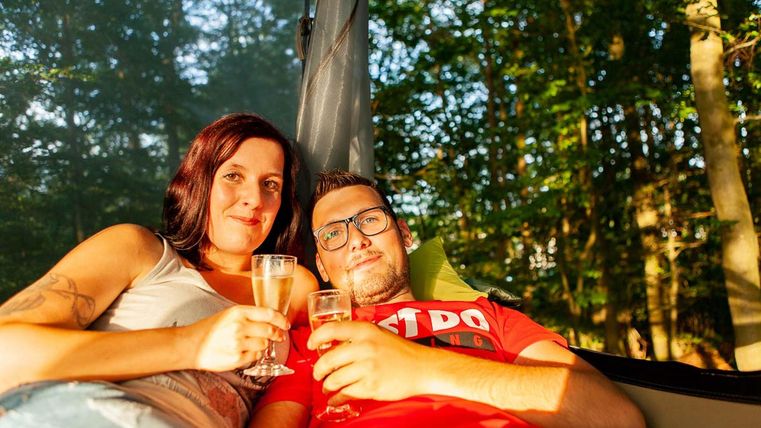 Twee mensen in een hangmat met champagne