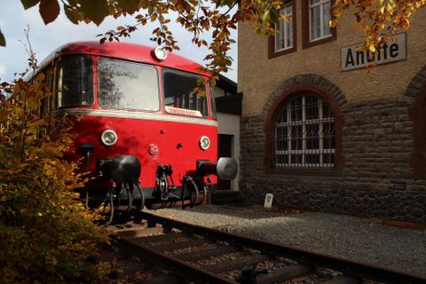 A red rail bus stands in front of the museum building