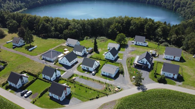 Eine ruhige Wohnsiedlung mit modernen Häusern liegt in der Nähe eines klaren Sees. Umgeben von grünen Wiesen und Bäumen ist die Umgebung sehr idyllisch.