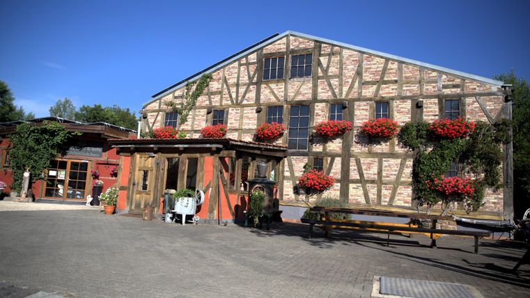 Auf dem Bild erkennt man eine Fachwerkhaus, was mit Blumen verziert ist, Die Sonne scheint und der Himmel ist wolkenfrei
