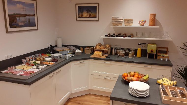 Eine gemütliche Frühstücksecke mit verschiedenen Speisen und Getränken. Auf dem Tisch sind frisches Obst und Gebäck angerichtet.