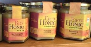 Three jars of honey with colorful labels. The varieties are "Organic Honey", "Spring Honey", and "Flower Honey".