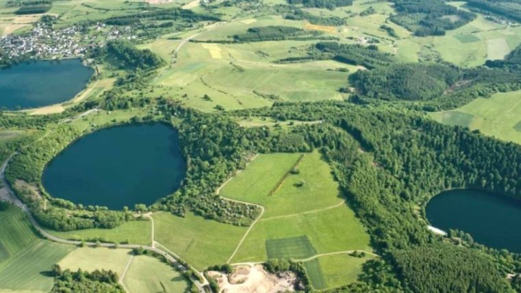 A vast landscape with several lakes and rolling fields. Green terrain and forests characterize the surroundings.