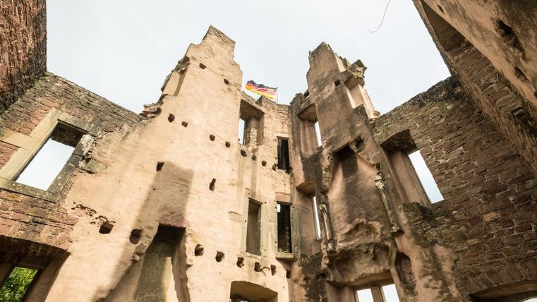 Ruins of an old building with open windows and a flag at the top. The structure has a distinctive, weathered facade and is surrounded by natural surroundings.