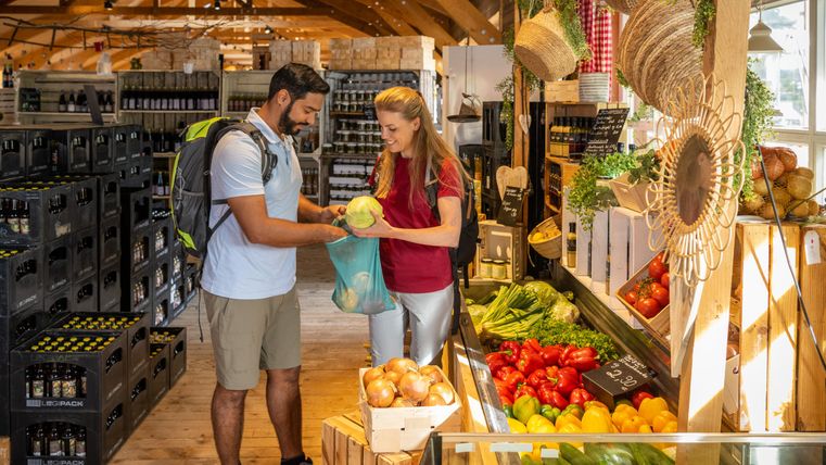 Ein frischer Marktplatz mit Obst und Gemüse. Zwei Personen interagieren beim Einkaufen in einem einladenden Laden.
