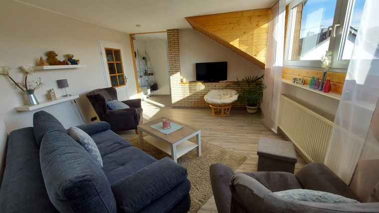 A cozy living room with a modern interior. There is a sofa, a coffee table, and large windows that let in plenty of light.