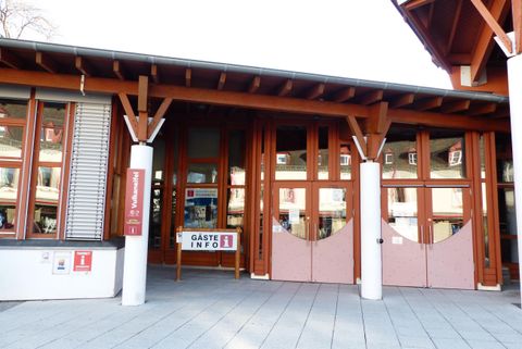 Eine moderne Eingangstür mit Holzrahmen und großen Fenstern. Der Bereich wirkt einladend und gut beleuchtet.