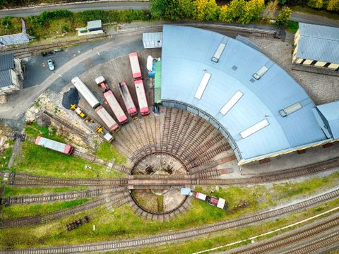 Een Vogelperspectief op een stationsgebied met meerdere wagons en een driesporige spoortak. Het ronde spoorsegment is goed zichtbaar en wordt omringd door een grote hal.