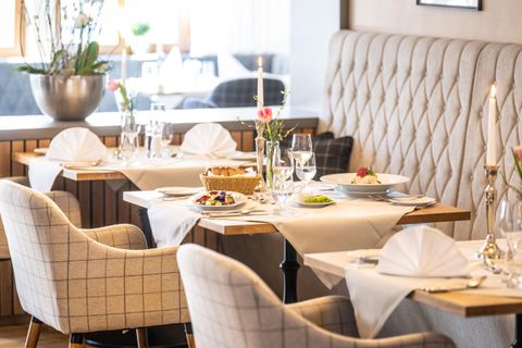 Een elegant restaurant met stijlvolle tafels en comfortabele stoelen. De tafeldecoratie bestaat uit bloemen en gedekte borden, wat een aangename sfeer creëert.