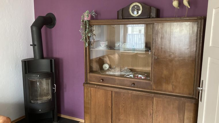 Een gezellige ruimte met een houten vitrine en een moderne open haard. De muur is in een krachtige paarse kleur geschilderd.