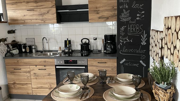 Een moderne keuken met houten planken en een eetruimte. De tafel is gedekt met servies en decoratieve planten.