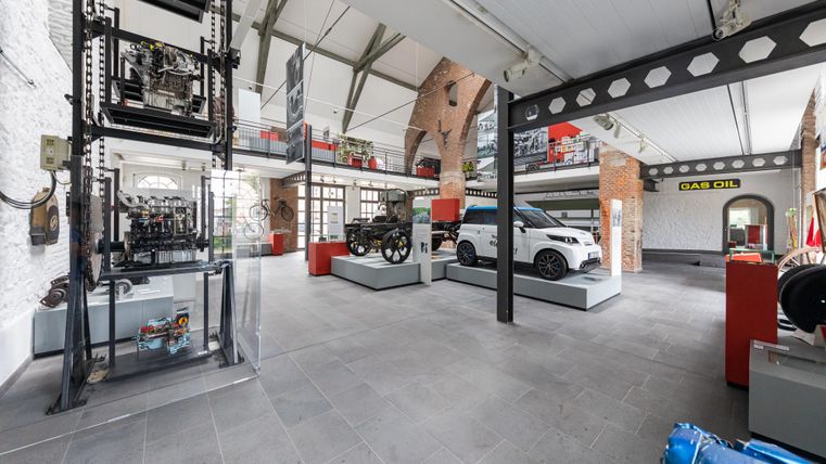 A modern exhibition building with various vehicles and machines. The space is bright and open, with an industrial style.