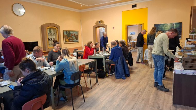 A cozy room with several tables where people eat together and converse.