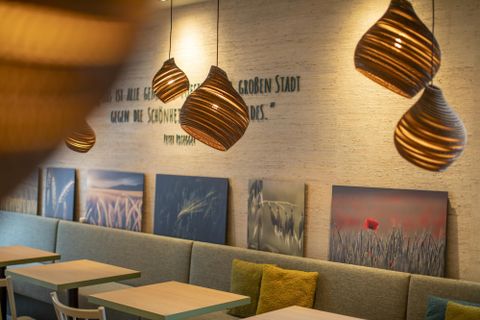 Een modern restaurant met een gezellige sfeer. Plafondlampen en decoratieve wanddecoraties creëren een uitnodigende ambiance.