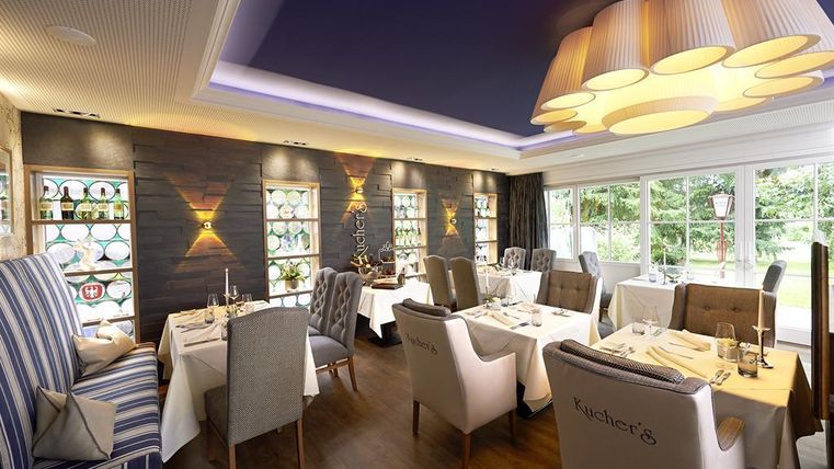 Ein elegantes Restaurant mit stilvollen Möbeln und einer warmen Atmosphäre. Am Tisch sind schicke Tischdecken und Kerzen dekoriert.