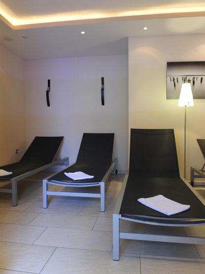 Ein entspannender Raum mit modernen Liegen und sanfter Beleuchtung. Die Umgebung wirkt ruhig und einladend.