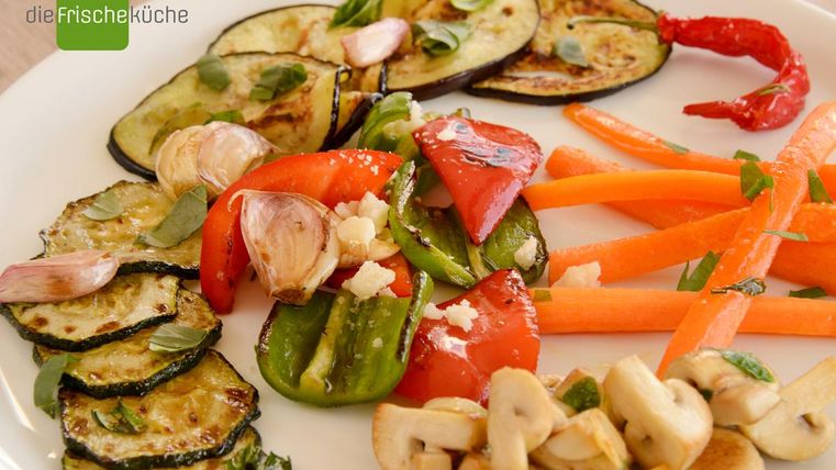 Ein buntes Gemüsegericht mit gegrillten Zucchini, Paprika, Karotten und Knoblauch. Frische Kräuter und ein Hauch von Farbe machen es appetitlich.