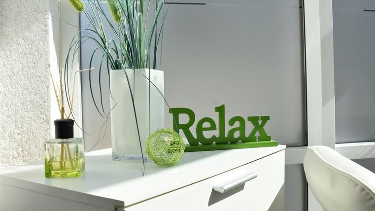 Ein ruhiger Tisch mit einer Blume und einer dekorativen Vase. Ein grünes "Relax"-Schild fördert eine entspannte Atmosphäre.