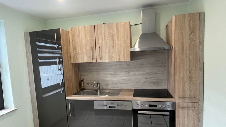 Modern kitchen with wood and glass elements. It features a stove, a refrigerator, and a sink.