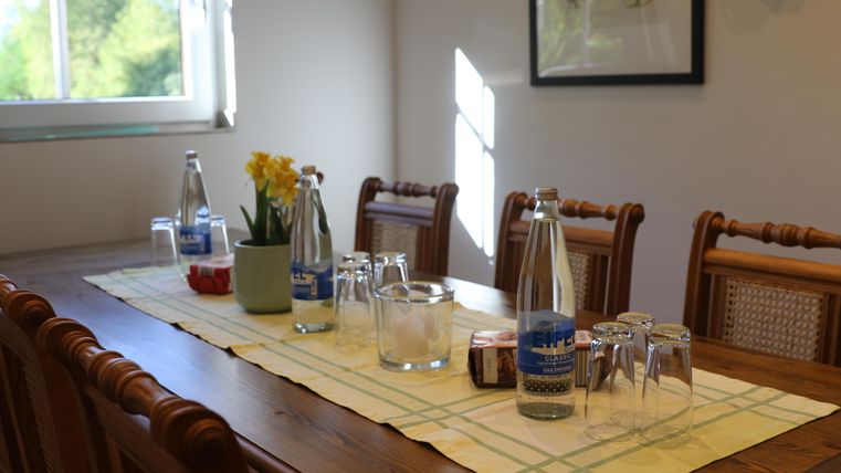 An inviting table with water bottles, glasses, and a floral decoration. The sunny atmosphere creates a pleasant mood in the room.