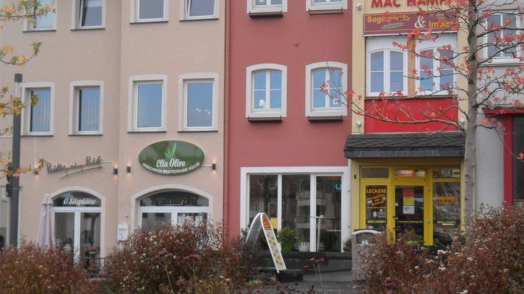 Een reeks gebouwen in een stad. Enkele winkels zijn zichtbaar, waaronder een restaurant en een snackbar.