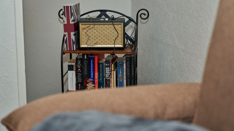 A cozy living area with a bookshelf and a vintage box. In the background, a British flag can be seen.
