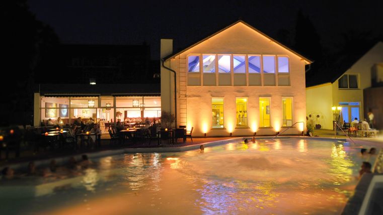 Een mooi zwembad bij nacht, omgeven door verlichte gebouwen. Zachte lichten weerkaatsen op het water.