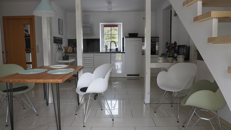 Eine moderne Küche mit einem Essbereich. Der Raum ist hell und freundlich eingerichtet, mit einem Tisch und weißen Stühlen.