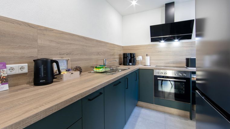 Eine moderne Küche mit Holz- und dunklen Küchenschränken. Sie ist gut ausgestattet mit Elektrogeräten und hat viel Tageslicht.