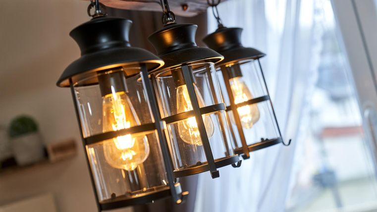 Three historical lanterns hang from the ceiling and radiate warm light. The background is bright and cozy.