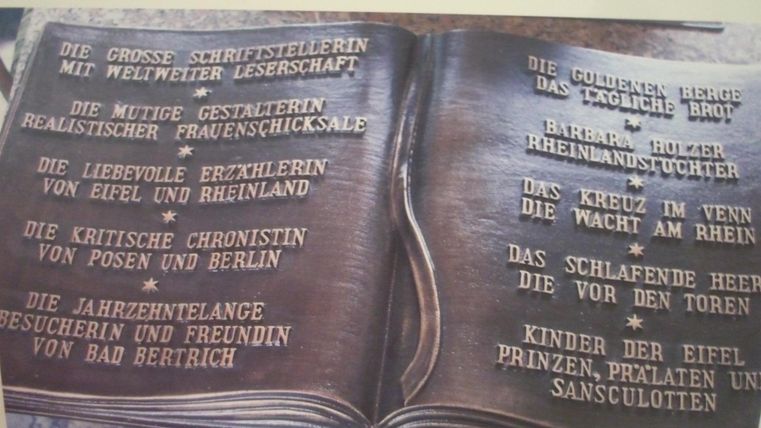 Ein offenes Buch mit eingravierten Texten, das an Clara Viebig und ihr literarisches Erbe erinnert. Dieser Teil des Denkmals befindet sich in Bad Bertrich.