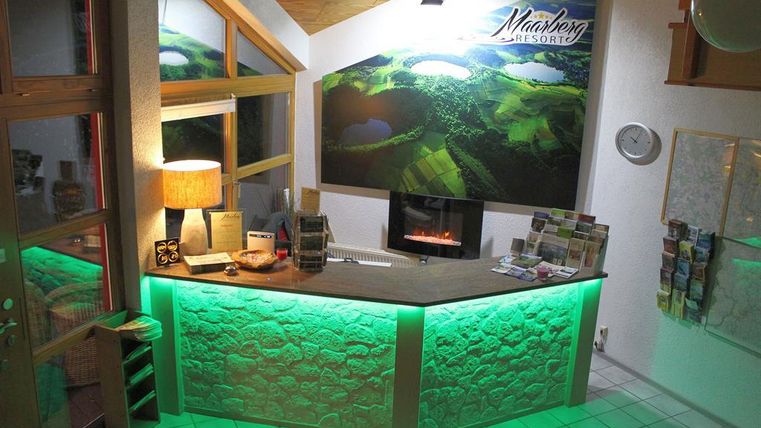 Ein Empfangsbereich mit freundlichem Ambiente und modernem Design. Die gemütliche Beleuchtung und die grüne Lichtakzentuierung verleihen dem Raum eine einladende Atmosphäre.