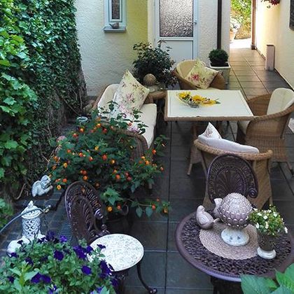 Eine gemütliche Terrasse mit bequemen Möbeln und vielen Pflanzen. Der Raum ist hell und einladend, ideal zum Entspannen.