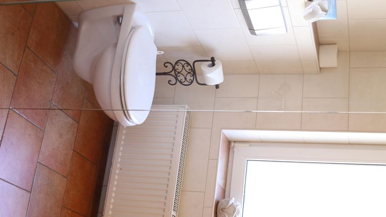 Ein sauberes Badezimmer mit einer Toilette und einem Fenster. Der Boden ist gefliest und es gibt einen Handtuchhalter.