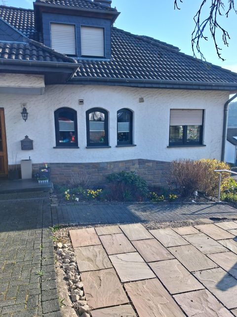 A modern residential building with a paved path and a small garden. The windows are fitted with shutters and the facade is brightly painted.