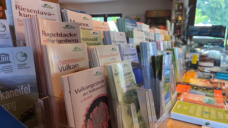 Een tafel met verschillende informatiefolders en brochures over natuur en wandelbestemmingen. De omgeving lijkt uitnodigend en informatief.
