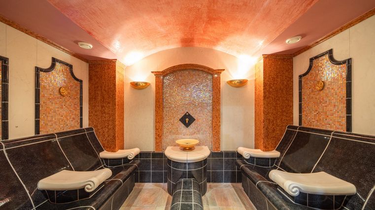 Een elegante wellnessruimte met stijlvolle ligstoelen en zachte verlichting. De muren zijn ingericht met stijlvolle tegels en houten versieringen.