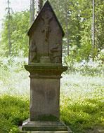 A stone monument stands in a green meadow. Surrounded by trees, it conveys a peaceful atmosphere.