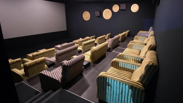 Een gezellig theater met comfortabele stoelen en een groot scherm. De wanden zijn donker geschilderd en gedecoreerd.