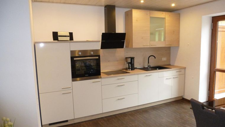 Eine moderne Küche mit weißen Schränken und einer offenen Arbeitsfläche. Die Geräte sind in einem eleganten Design gehalten und die Beleuchtung sorgt für eine helle Atmosphäre.