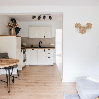 Eine moderne Küche mit einem Esstisch und Stühlen. Die Wände sind hell und die Einrichtung wirkt freundlich und einladend.