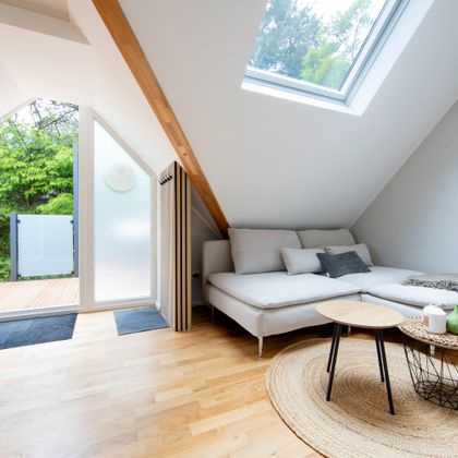 Een moderne, lichtovergoten kamer met een gezellige bank en een kleine tafel. Grote ramen bieden uitzicht op een groen buitengebied.