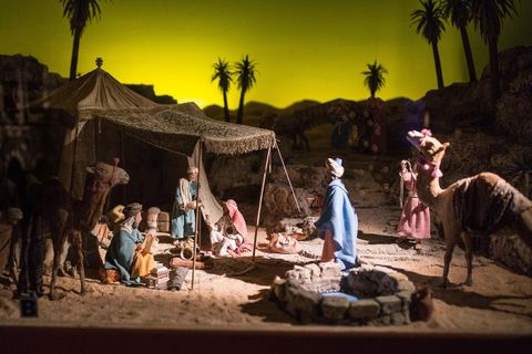 Een kersttaferelen met figuren in een woestijnlandschap. Tentjes, kamelen en palmbomen zijn op de achtergrond te zien.