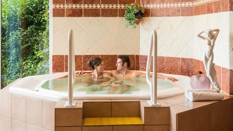 Ein romantisches Badezimmer mit einem Whirlpool. Ein Paar entspannt sich in der Wanne und genießt die Zeit zusammen.