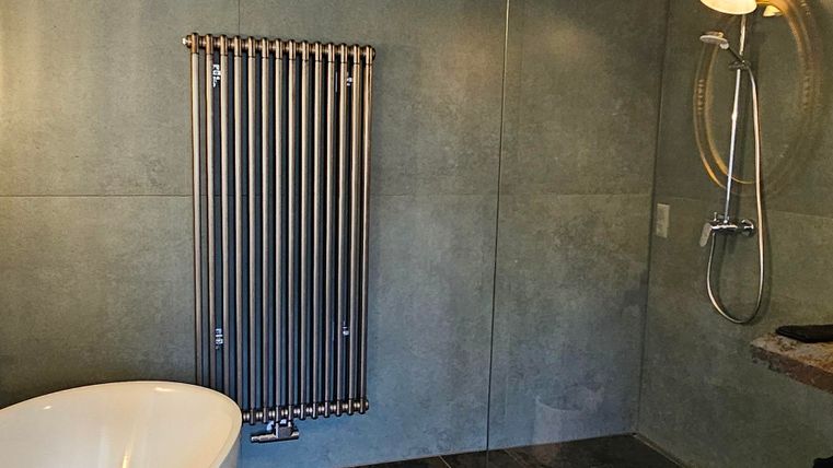 A modern bathroom with a freestanding bathtub and a separate shower. The walls are in an elegant gray tone, and the floor is made of dark stone.
