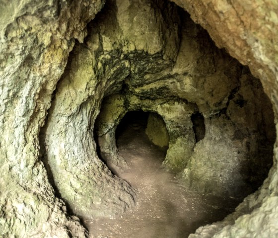 De ingang van de Buchenloch Grot heeft ongelijke, natuurlijke rotswanden en een donkere tunnel binnenin., © Eifel Tourismus GmbH, Dominik Ketz