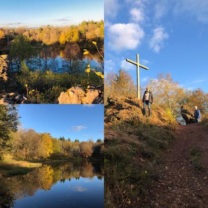 A beautiful landscape with lakes and autumn trees. In the background, there is a cross on a hill under a clear sky.