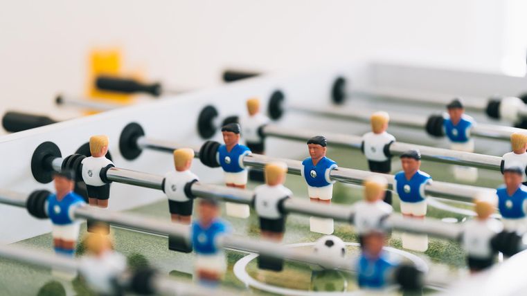 Een tafelvoetbalspel met veel kleurrijke figuren. De spelers staan op een groen speelveld en zijn klaar om te spelen.