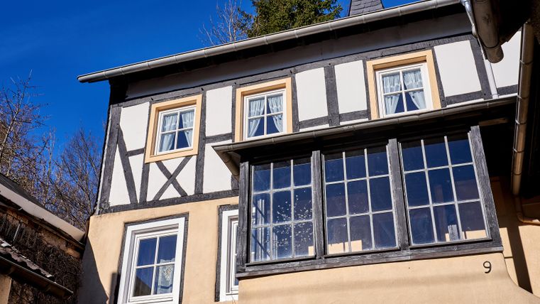 A charming half-timbered house with a bright extension and large windows. The blue sky gives the scene a friendly atmosphere.