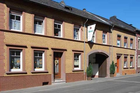 A multi-story, bright building with an entrance in the middle. The facade has yellow and red bricks and windows with curtains.
